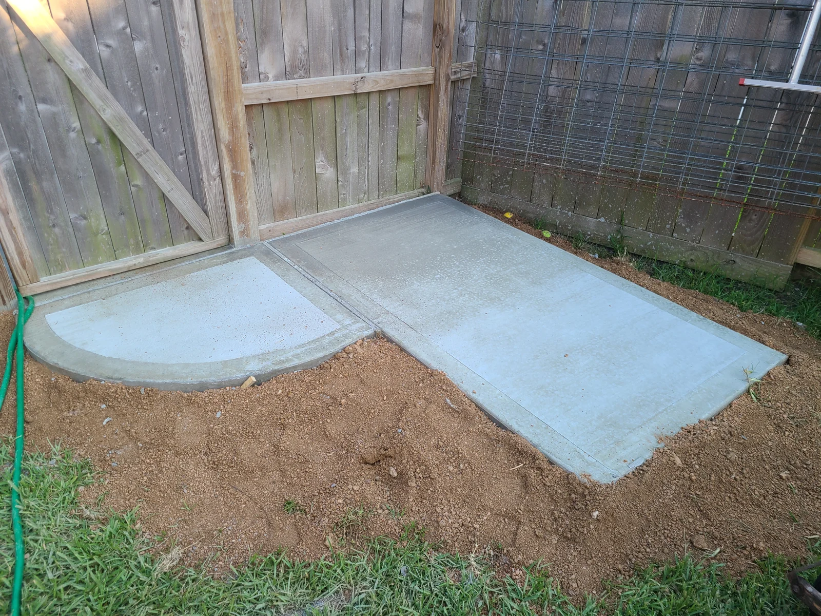 Compact concrete patio with curved corner at a fence