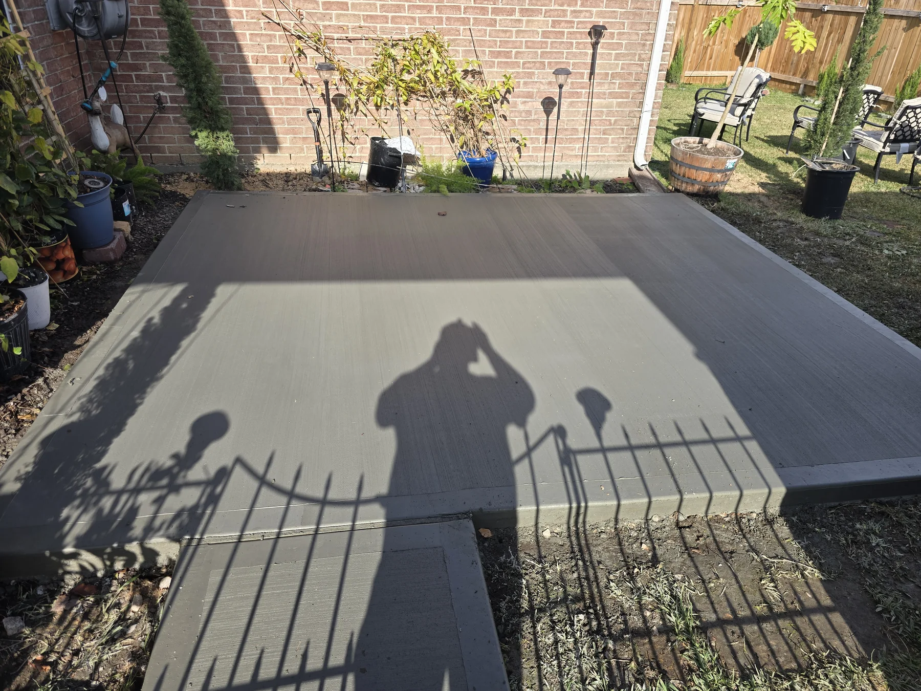 Freshly poured backyard concrete patio and connecting path, photographed December 2025