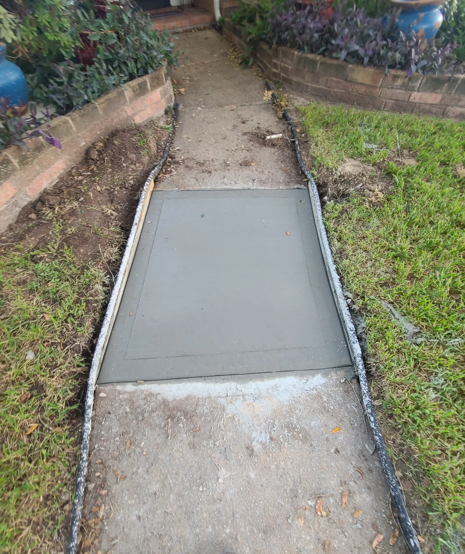 Replacement concrete panel in an existing residential walkway, photographed September 2023
