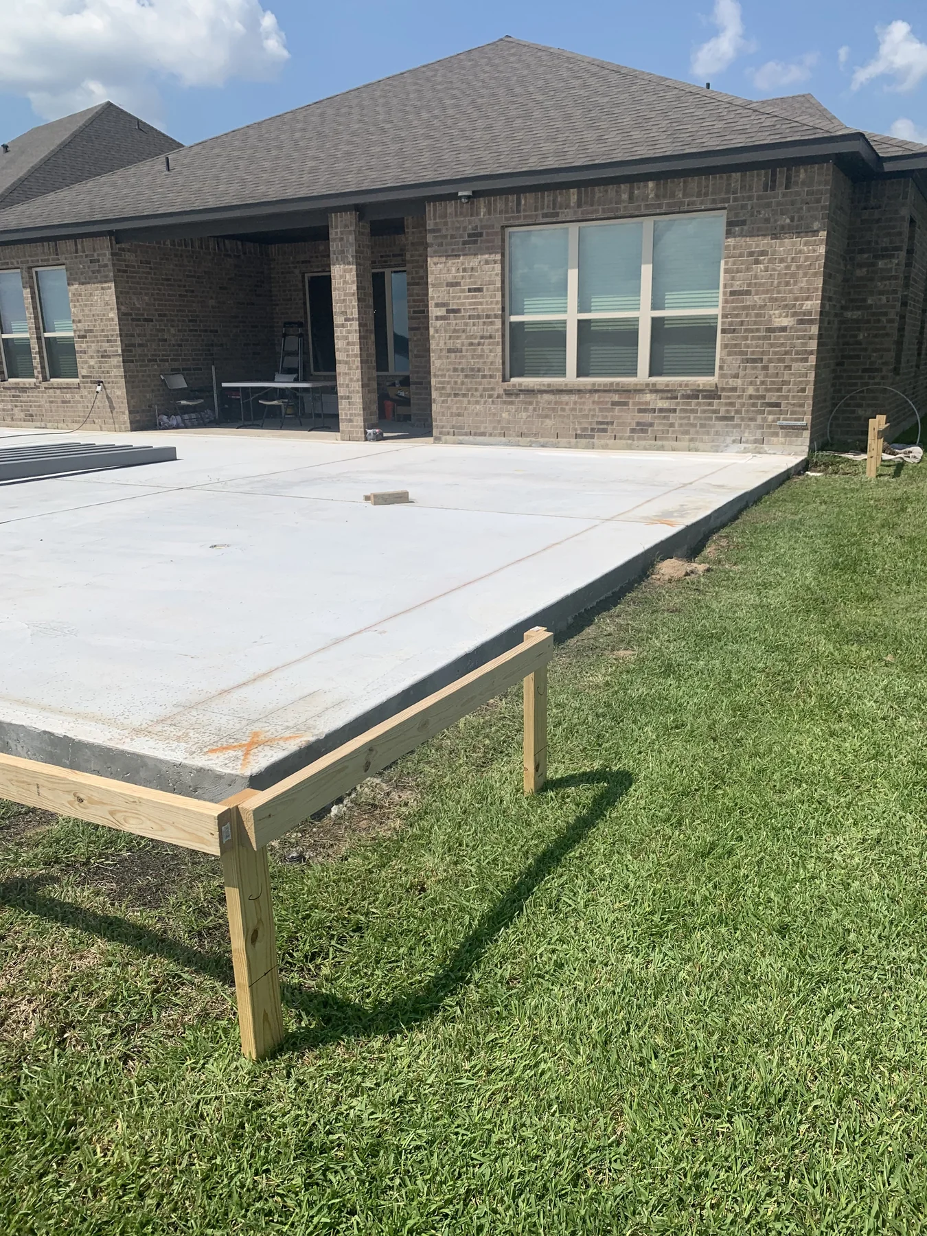 Large concrete patio slab beside a brick home after the pour, photographed September 2022